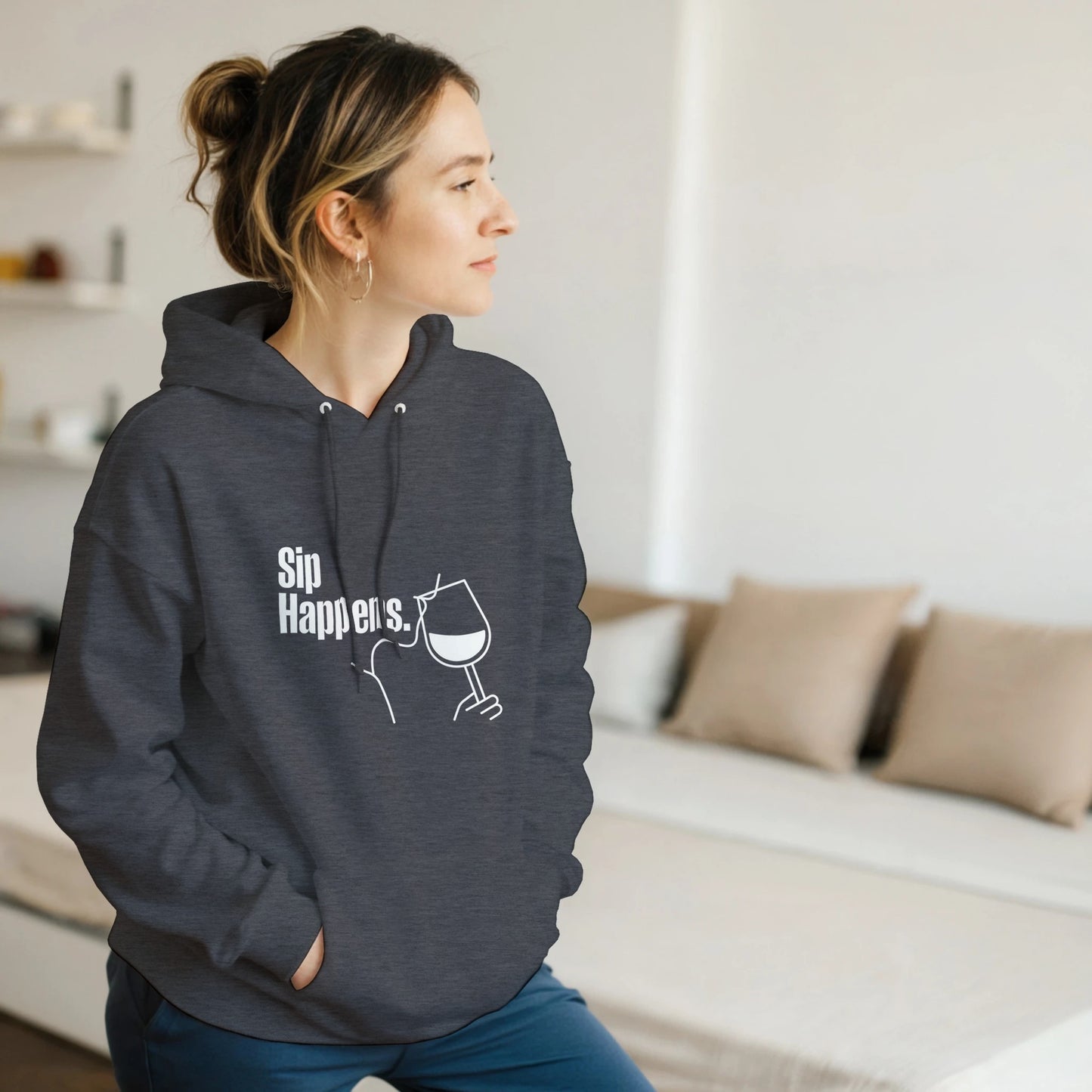 Person wearing a dark gray hoodie with 'Sip Happens' text and graphic, sitting in a room.
