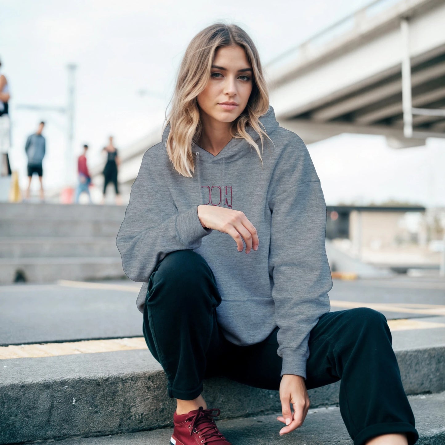 Grey hoodie with red embroidery reading ‘Ooh La La!’ worn by model outdoors. Sustainable unisex hoodie by Taste Union.