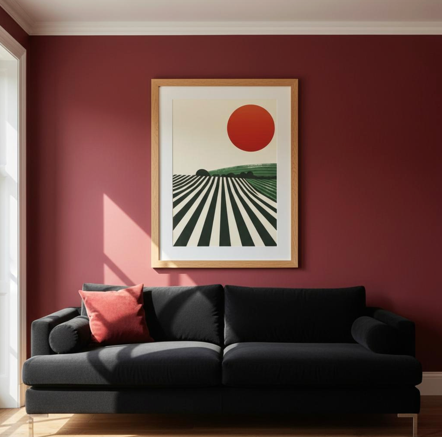 Framed vineyard sunset art print by Taste Union featuring a deep red sun above green vineyard lines — styled in a rich wine-red living room with a black sofa for a bold, modern statement.