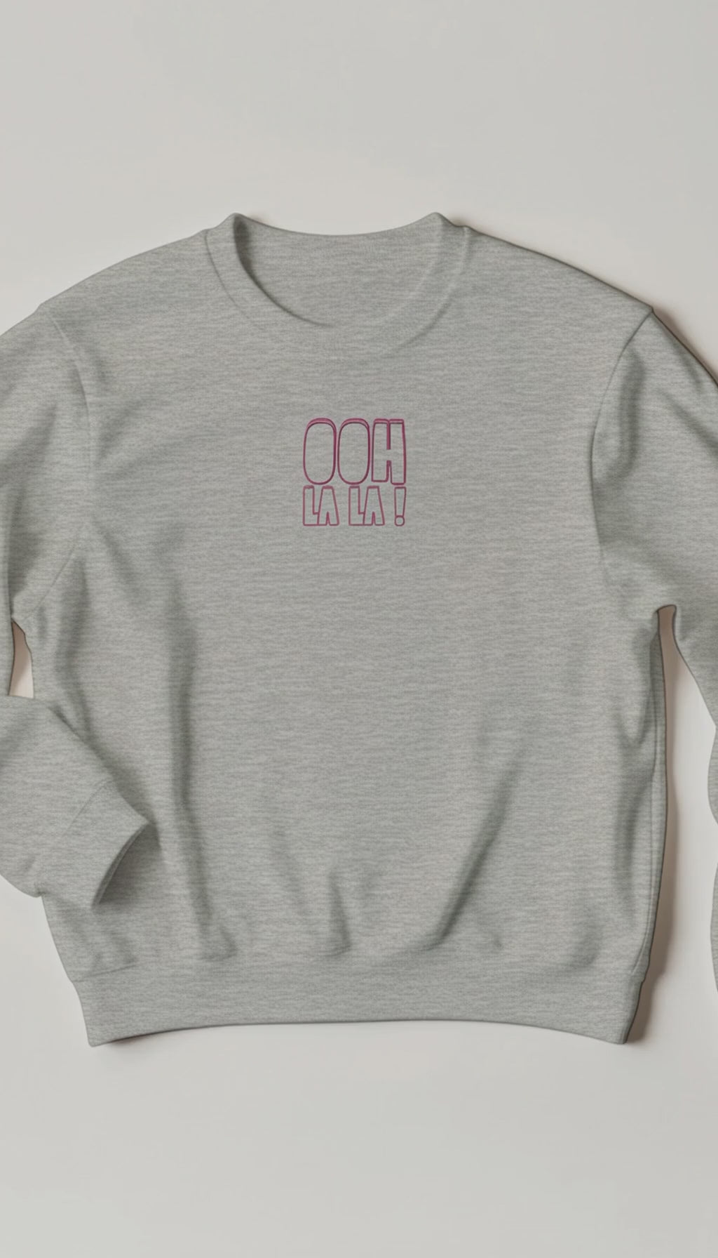 A woman at home wearing the pink “Ooh La La” sweater, smiling as she talks about how fabulous it feels. The cosy setting and natural lighting highlight the sweater’s relaxed, confident vibe — capturing warmth, comfort, and effortless style.