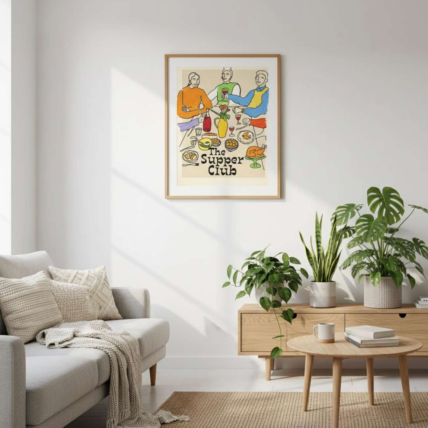 The Supper Club Poster displayed in a modern living room interior with sofa, coffee table, and house plants. Dining room wall art print featuring a colorful illustration of three people sharing food and wine. Perfect for kitchen wall decor, bar art, foodie prints, and gifts for wine lovers. Sustainable matte poster framed and styled in a contemporary home setting