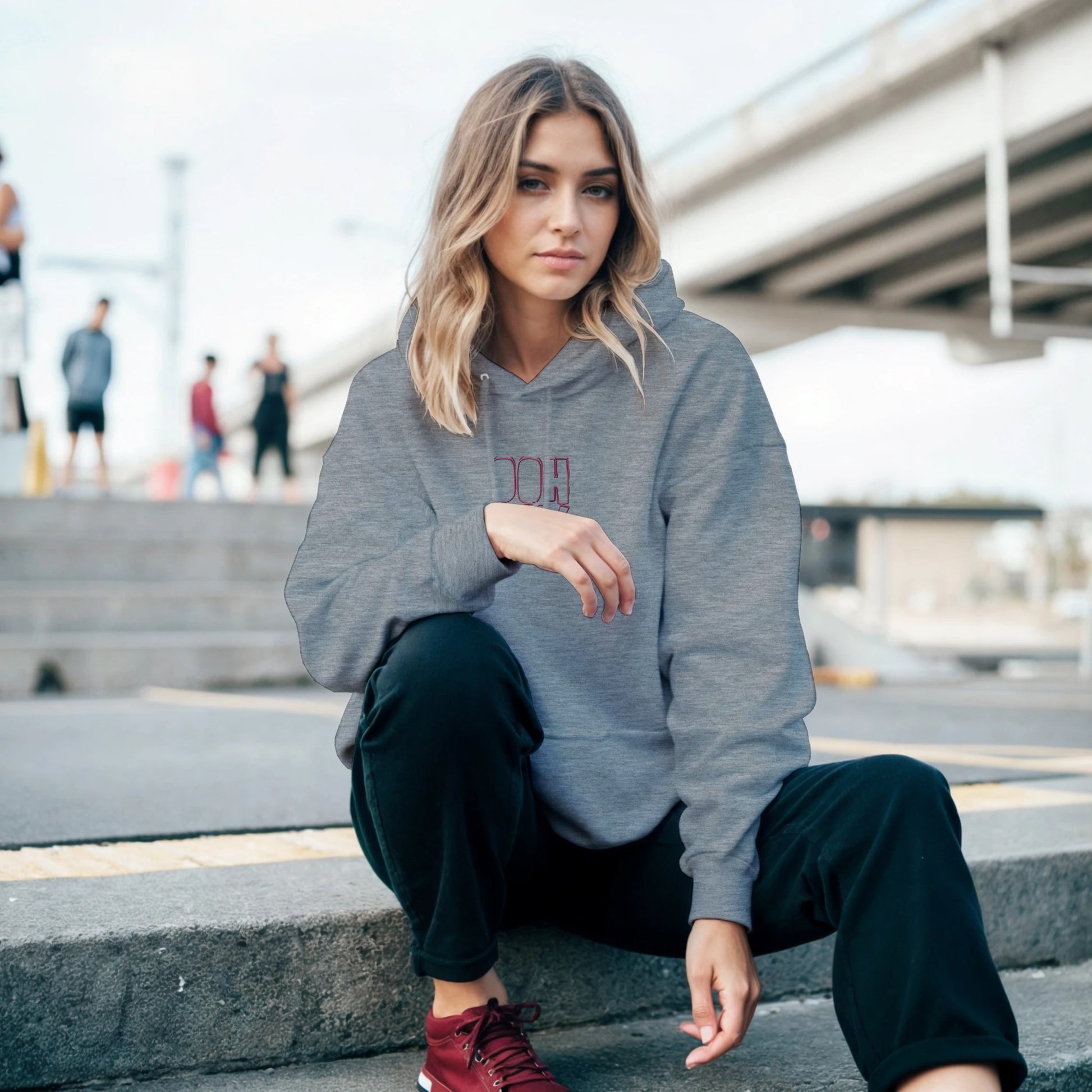 Grey hoodie with red embroidery reading ‘Ooh La La!’ worn by model outdoors. Sustainable unisex hoodie by Taste Union.