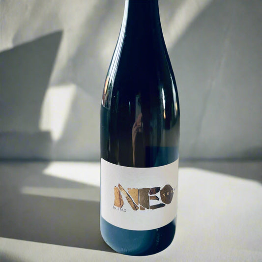 A bottle of La Nouvelle Don(n)e NEO 2020 white wine with a minimalist label, placed on a white surface, showcasing its elegant design and branding.