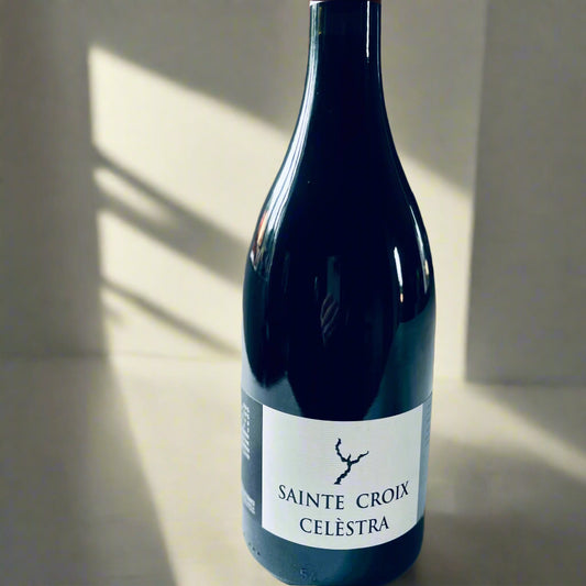 A bottle of Domaine Sainte Croix Celestra 2019 red wine on a light surface, showcasing its elegant black label with a minimalistic design and clear branding.